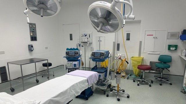 A new stark white operating theatre with a bed and machines.
