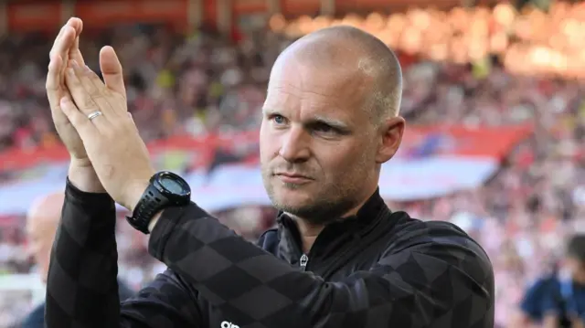 Liam Manning applauding from the touchline.