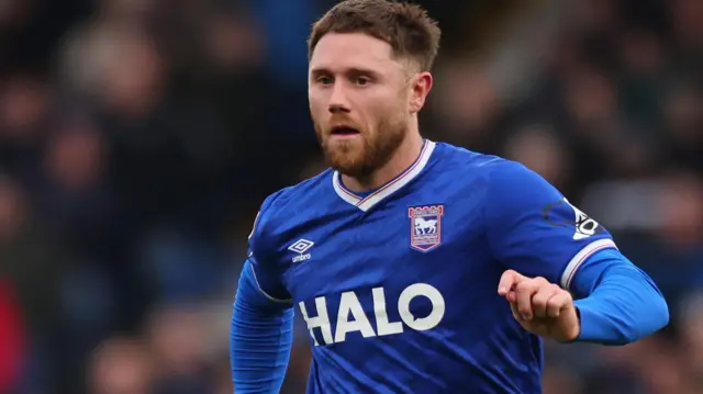 Wes Burns in a blue Ipswich Town shirt and white shorts running with the ball in a recent game against Leicester