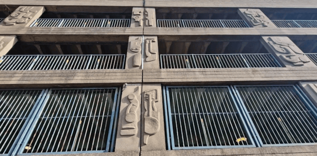 10 concrete pillars adorned with abstract designs that protrude from the concrete panels. In between the pillars are railings.