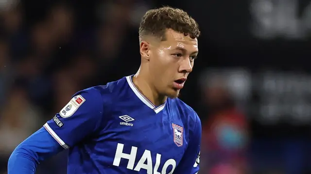 Kasey McAteer, wearing a navy blue shirt with white trim, in action for Ipswich Town