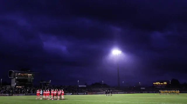 The Derry and Donegal teams stand for the National Anthem ahead of the 2024 Dr McKenna Cup final at Healy Park 