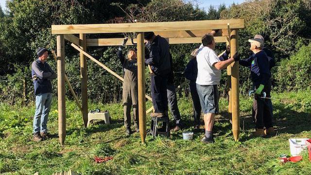 People working on building a wooden shed