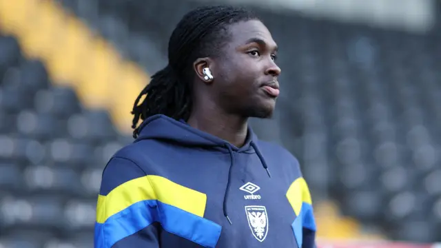 Osman Foyo while at AFC Wimbledon with a blue hoodie on and a white air pod in his ear.