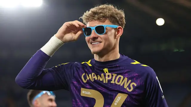 Carl Rushworth celebrates with Coventry. He wears shades and a t-shirt which reads Champions 26.