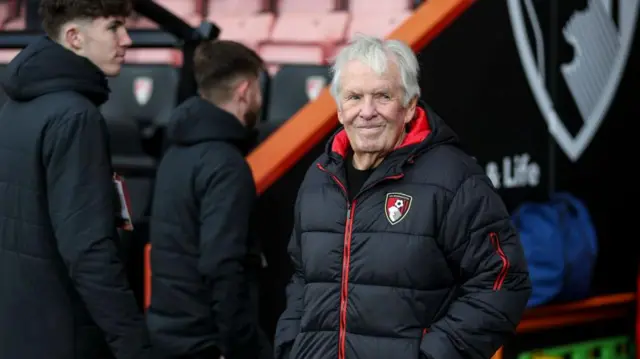 Bill Foley stands and smiles in a Bournemouth coat