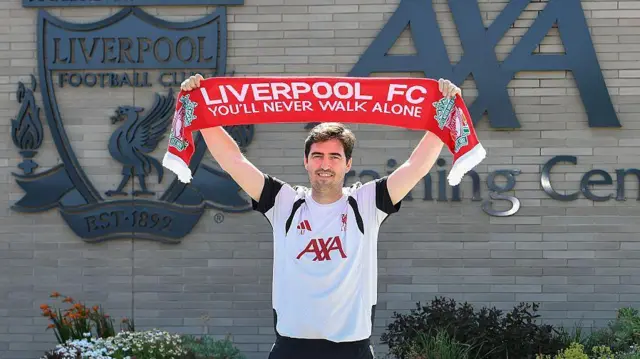 Andoni Iraola holding a Liverpool scarf above his head outside the Reds' training ground
