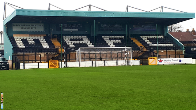 A view of the main stand at Marine FC's current stadium on College Lane, which has banks of white seats spelling the letters MAFC against a background of blue