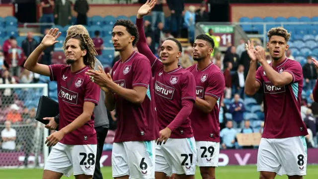 Burnley's players, wearing their claret home shirts, wave and applaud to fans on a lap of honour after the 2-2 draw with West Ham at Turf Moor