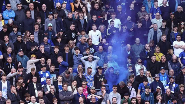 Everton fans with blue smoke in the crowd