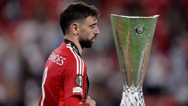 Bruno Fernandes walks past the Europa League trophy
