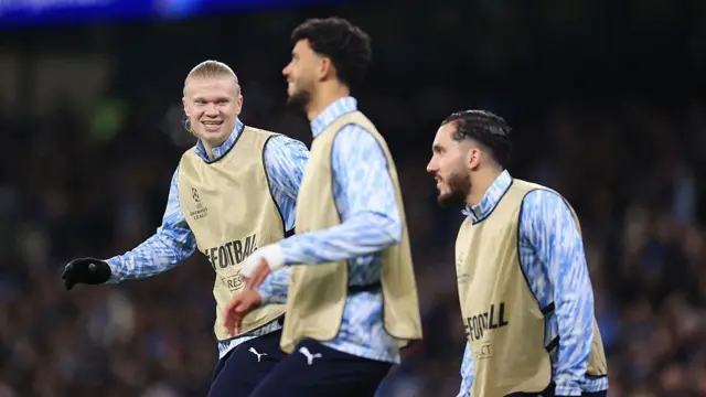 Erling Haaland smiles as he warms up with Matheus Nunes and Rayan Cherki