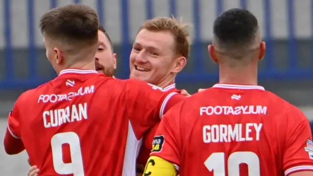 Shea Gordon is congratulated by Cliftonville team-mates after netting the Reds' second goal at Mourneview Park