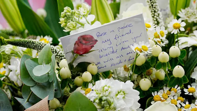 A handwritten card in the bunch of flowers brought by Jordan Henderson. It reads: Rest in peace, my friend, along with your brother Andre. We will all miss you. Love Hendo and family."