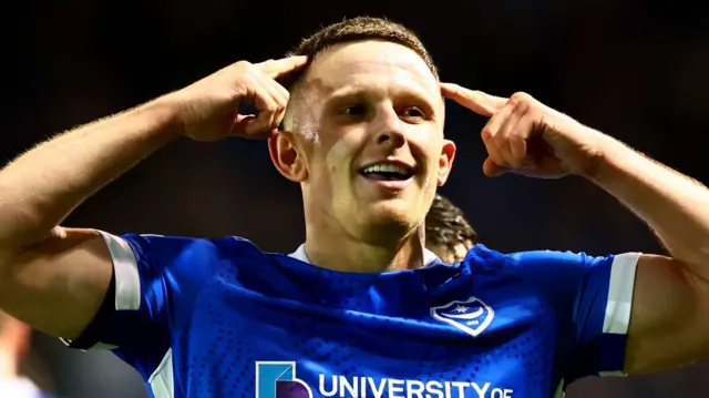 Colby Bishop points to his temples after scoring Portmouth's second goal against Ipswich