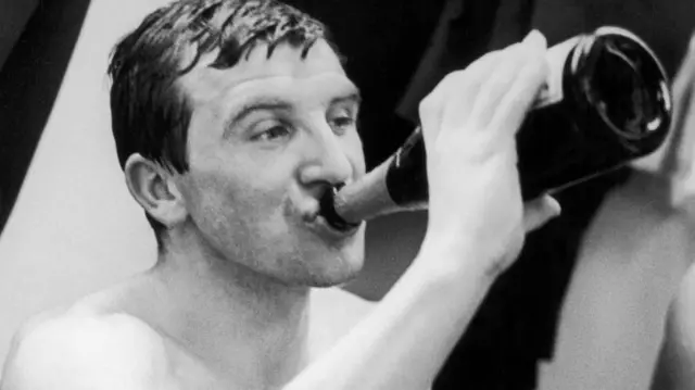 Johnny Morrissey drinking from a bottle of champagne
