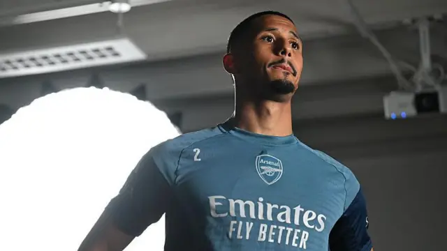 William Saliba looks on with bright light in background before photoshoot