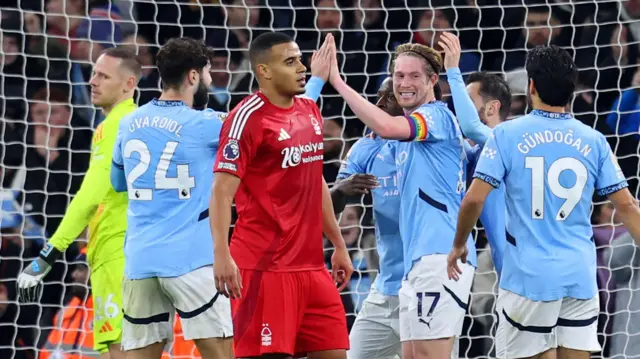 Manchester City players celebrate a goal while Nottingham Forest players look on