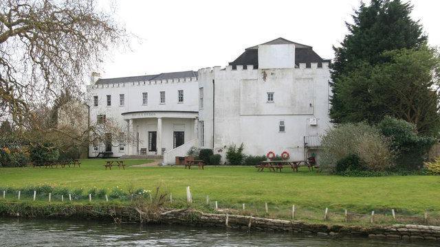 Bray studios white 18th century house sat next to a body of water and surrounded by green grass and trees