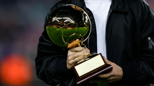 Close-up of the Golden Boy trophy - shaped like a golden football - being held 