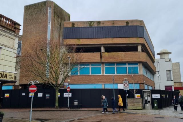 The building before it was refurbished into a library. It stands three storeys tall and has black boarding preventing people from entering.