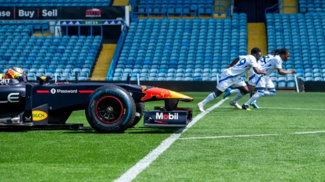 Leeds United players race against a Red Bull F1 car