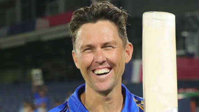 Trent Brent holds up his bat and smiles in celebration