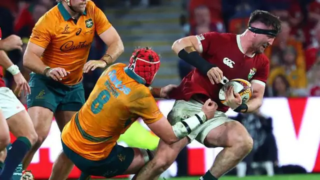 Australia's Harry Wilson (C) tackles British and Irish Lions' Tom Curry.