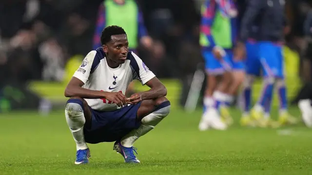 Pape Matar Sarr crouching on the pitch and looking dejected