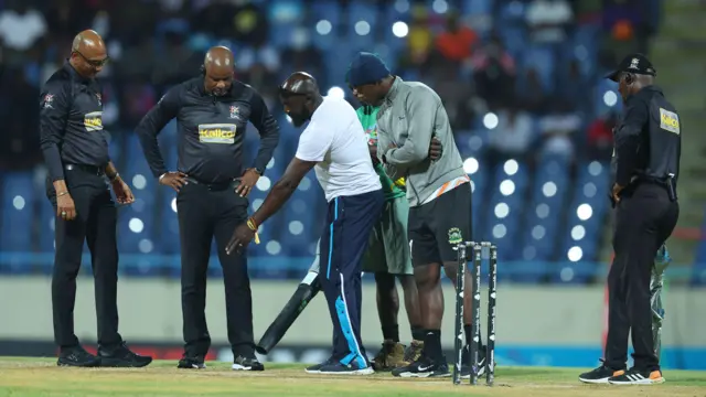 Umpires and groundstaff inspect the pitch for Antigua and Barbuda Falcons' match against Saint Lucia Kings in the Caribbean Premier League