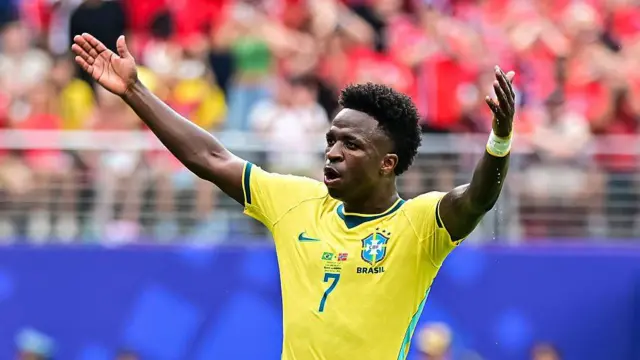 Vinicius Jr playing for Brazil. His arms are aloft.