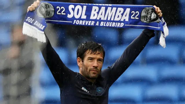 Brian Barry-Murphy holds up a scarf in tribute to Sol Bamba