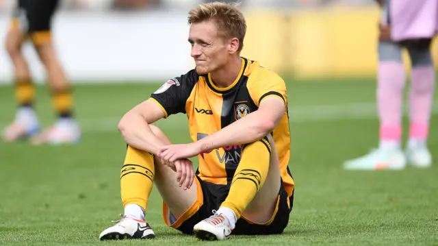Newport County midfielder Matt Smith is dejected on the pitch after losing to Milton Keynes Dons at Rodney Parade
