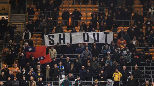 Empty seats and Wolves fans holding up a banner that says 'SHI OUT'