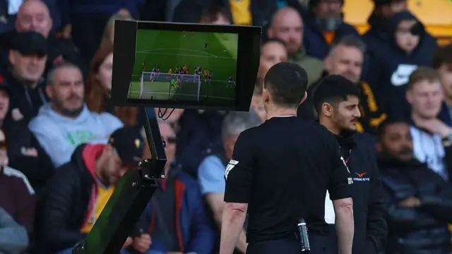 Referee Tony Harrington reviews decision on VAR monitor