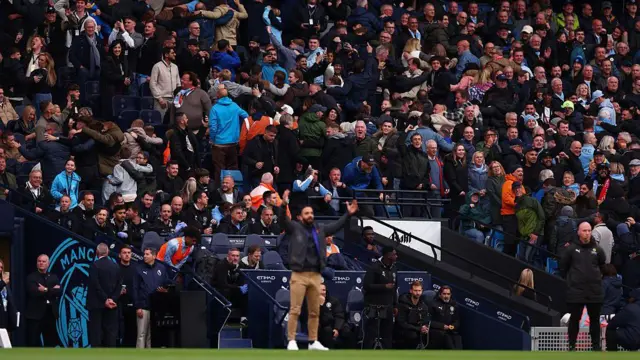 Manchester City fans do the Poznan behind Manchester United Manager Ruben Amorim