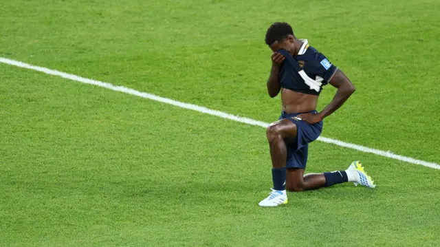 Jose Cordoba, wearing his deep navy Panama third kit, kneeling on the pitch and lifting his shirt to this face after the side's loss to Croatia on Wednesday