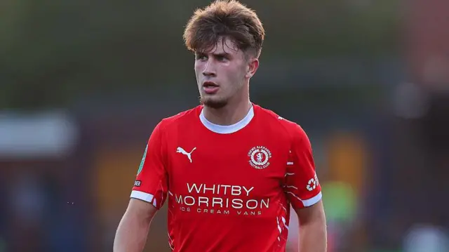 Luca Moore wearing a red Crewe Alexandra shirt looks on during a game