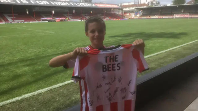 Young boy holding signed Brentford shirt inside Gtech Community stadium