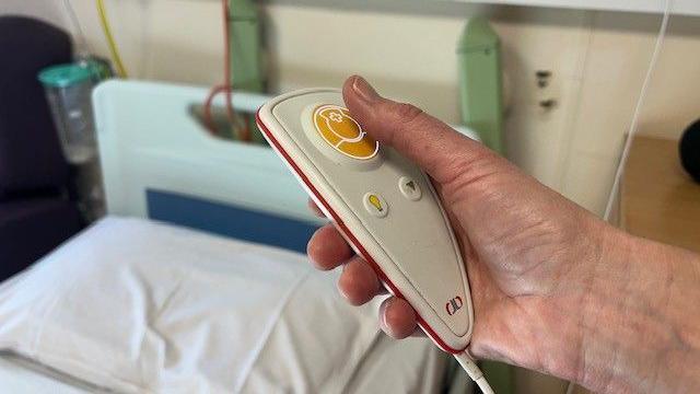 A person holding a hospital bed remote used to call the nurses.