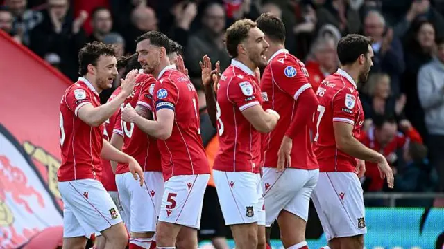 Wrexham players Ollie Rathbone (left), Dom Hyam (second left) and Sam Smith (centre) celebrate with team-mates