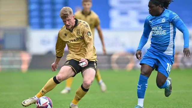 Andy Cannon is challenged by Abraham Odoh during Wrexham's win at Peterborough