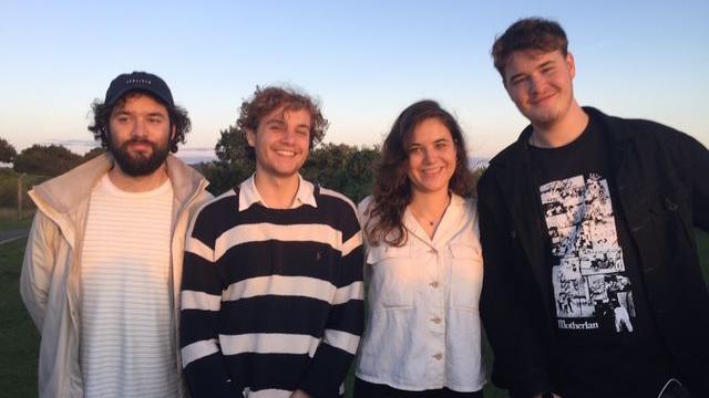 William Hewes is on the right and is the tallest and youngest of his siblings, who are two brothers and a sister. they are all smiling and close together standing in a line in a park