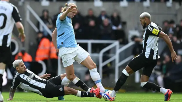 Manchester Erling Haaland (C) is tackled by Newcastle's Bruno Guimaraes and Joelinton