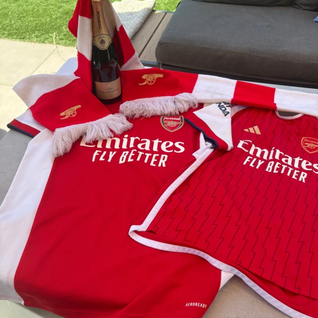 Arsenal shirts with a bottle of fizzy wine on top
