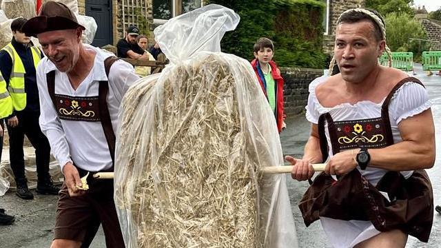 Two people dressed in a costume giving the appearance of a Lederhose and Dirndl - traditional clothing often worn in German-speaking countries.