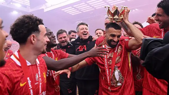 Mohamed Salah of Liverpool has the lid from Premier League trophy placed on his head as he celebrates with teammates as Liverpool are crowned the Champions of the Premier League for the 2024-25 Season 