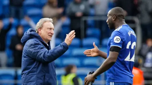 Former Cardiff City manager Neil Warnock (L) shakes hands with former Cardiff City defender Sol Bamba