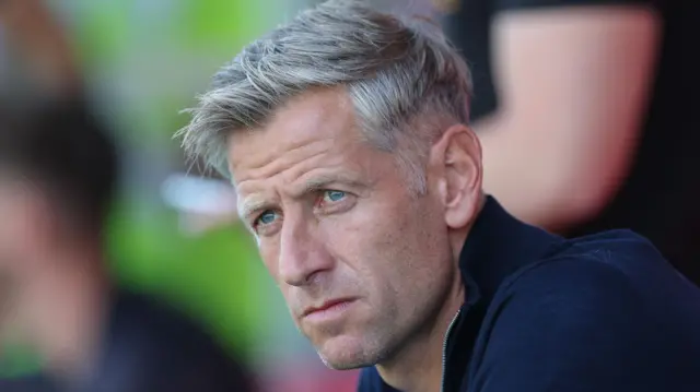 Newport County head coach David Hughes sitting in the dugout