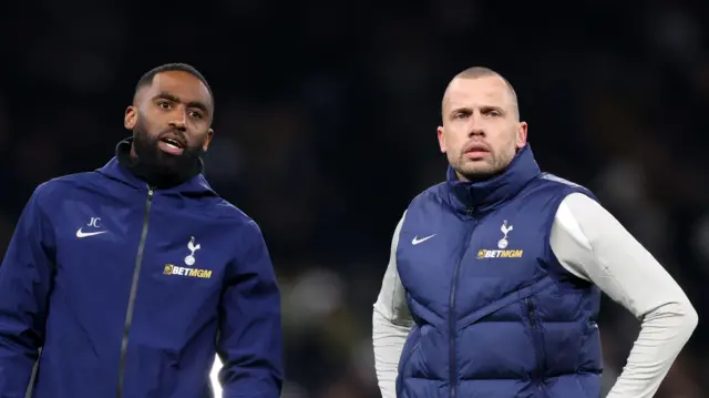 Justin Cochrane stands and talks to fellow assistant coach John Heitinga